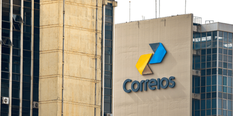 Fachada do edifício dos Correios em um dia de sol. O logotipo dos Correios, com três setas em amarelo, azul e cinza, está visível no prédio principal.