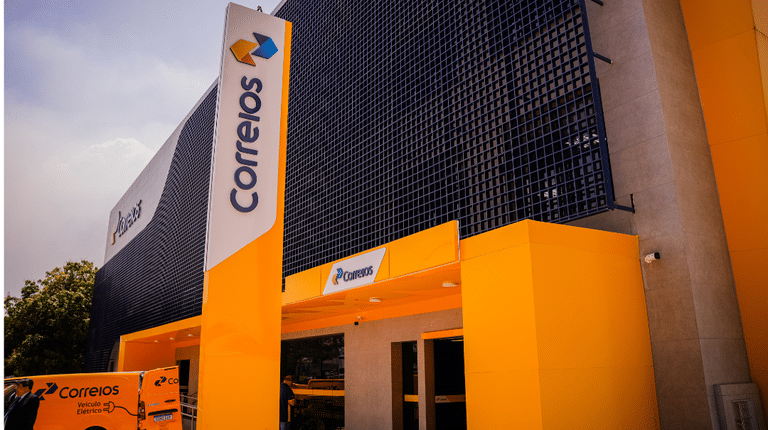 Edifício moderno dos Correios com o logo da empresa, representando a validade e a prorrogação do concurso público para os aprovados.