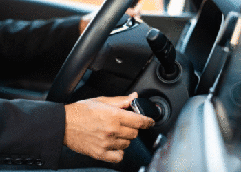 Homem tentando girar a chave na ignição do carro.