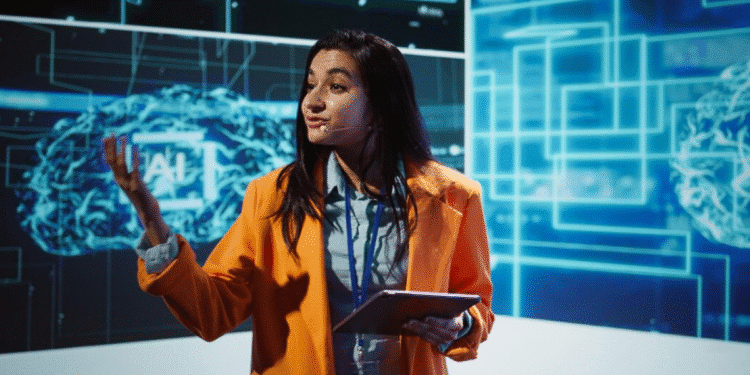 Mulher em uma apresentação, gesticulando enquanto fala sobre a evolução da Inteligência Artificial em um painel digital.