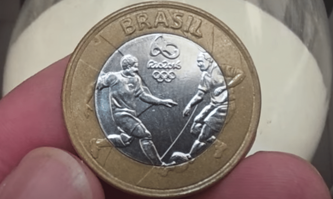 Moeda de 1 real de 2016 comemorativa do futebol. A imagem mostra o desenho de dois jogadores de futebol.