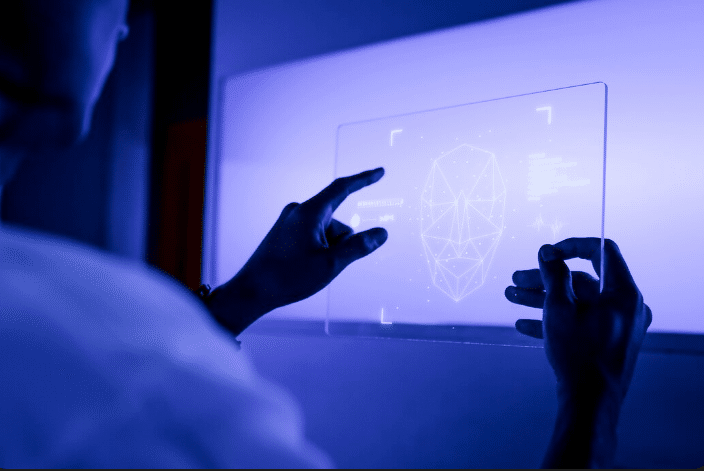 Pessoa interagindo com uma tela de realidade aumentada, exibindo um gráfico de reconhecimento facial. A imagem representa o avanço da inteligência artificial nas profissões.