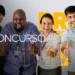 Grupo de quatro pessoas diversas sorrindo e mostrando sinal positivo com as mãos durante comemoração