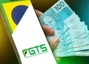 Pessoa verificando saldo do FGTS em celular enquanto segura cédulas de 100 reais, representando consulta sobre depósitos do FGTS em 2025.