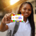 Estudante sorrindo segura cartão do programa Pé-de-Meia com design colorido em ambiente escolar