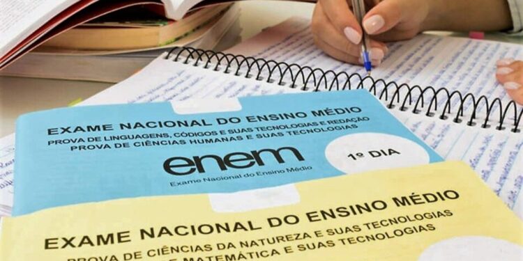 Estudante fazendo anotações com cadernos de prova do Enem sobre a mesa