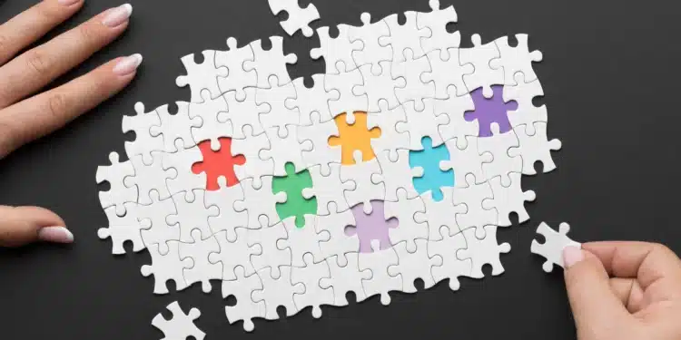 Imagem mostrando um quebra-cabeça com peças coloridas e uma mão segurando uma peça, representando a inclusão de jovens com TEA no programa de aprendiz do Bradesco.