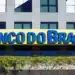 Fachada de uma agência do Banco do Brasil, destacando a placa com o nome da instituição em azul sobre fundo amarelo.