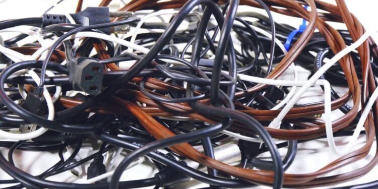 Um emaranhado de cabos e fios de diferentes cores, mostrando a desorganização de carregadores.