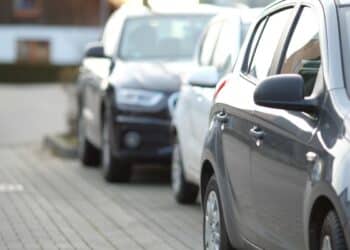 Carros estacionados sob o sol, representando os riscos de deixar objetos dentro do veículo no calor.