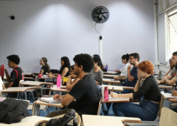 Estudantes sentados em sala de aula universitária prestando atenção na aula