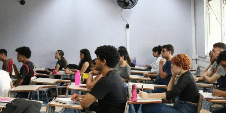 Estudantes sentados em sala de aula universitária prestando atenção na aula