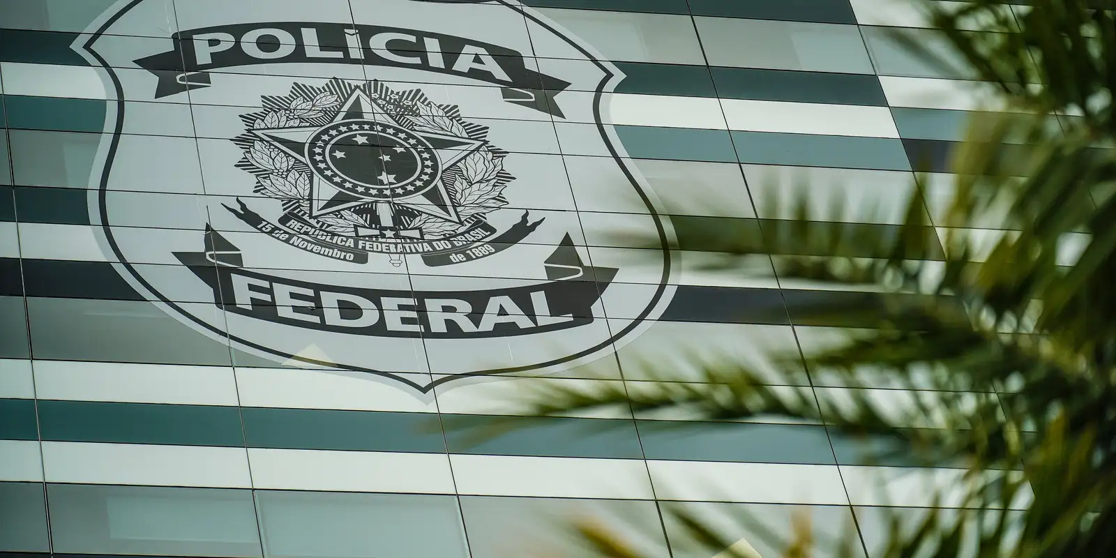 Fachada envidraçada com brasão da Polícia Federal do Brasil em destaque.