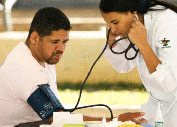 Mulher enfermeira em jaleco branco verifica pressão arterial de homem com aparelho de manguito