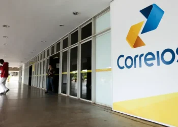 Sede dos Correios com pessoas saindo do prédio enquanto a logo da empresa é visível na imagem. Tema: concurso dos Correios após mudança de presidente.