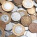 Moedas brasileiras de diferentes valores, como as de 1 real, 50 centavos e 5 centavos, espalhadas sobre uma superfície.
