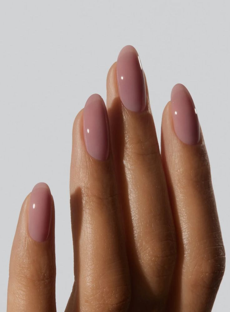 Mão com unhas pintadas de esmalte rosa claro, exibindo uma tendência de beleza para as unhas.