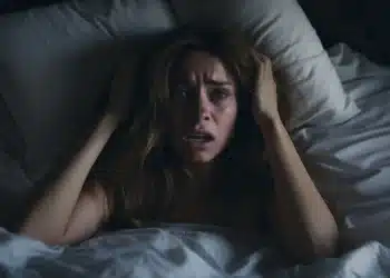 Mulher acordada em um susto, aparentemente com medo após sonhar que estava caindo da cama.