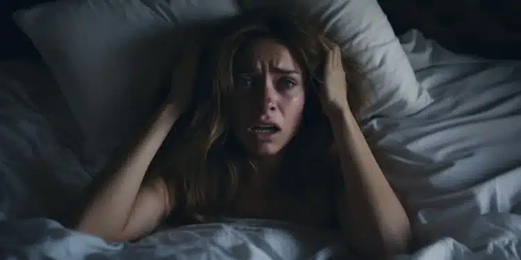 Mulher acordada em um susto, aparentemente com medo após sonhar que estava caindo da cama.