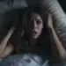 Mulher acordada em um susto, aparentemente com medo após sonhar que estava caindo da cama.