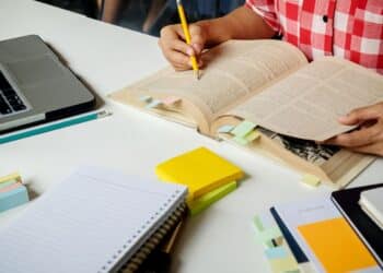 Pessoa estudando para concurso, com livros e notebook, representando a conciliação entre trabalho e estudos