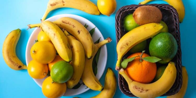 Vista superior de diferentes frutas, incluindo bananas e frutas cítricas, sobre uma superfície azul.