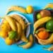 Vista superior de diferentes frutas, incluindo bananas e frutas cítricas, sobre uma superfície azul.