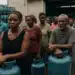 Pessoas em fila segurando botijões de gás