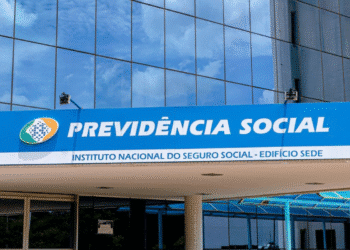 Fachada do Instituto Nacional do Seguro Social com logo e nome Previdência Social em prédio moderno com vidro refletindo o céu