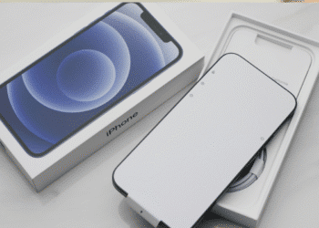 iPhone 12 preto com tela branca dentro da caixa ao lado da embalagem com imagem do aparelho