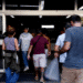 Grupo de pessoas caminhando para dentro de um edifício com a placa UERJ na porta de vidro