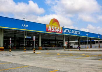 Fachada azul do atacadista Assaí com área de estacionamento vazia e carrinhos de compras alinhados.