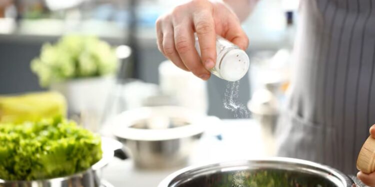 Pessoa adicionando sal na panela durante o preparo de uma refeição