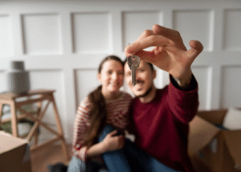Casal feliz segurando a chave de uma casa nova, comemorando a compra do imóvel."