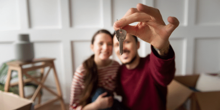 Casal feliz segurando a chave de uma casa nova, comemorando a compra do imóvel."