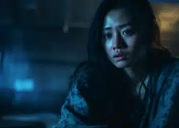 Mulher com expressão de medo em ambiente escuro, refletindo o temor do escuro comum até em adultos.