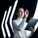 Mulher jovem interagindo com uma tela digital futurista, simbolizando as novas tecnologias e o aprendizado constante exigidos pelas profissões do futuro na indústria.