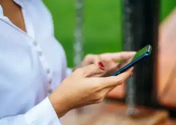 Pessoa segurando smartphone para anotações secretas no WhatsApp.