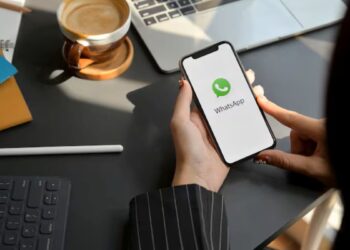 Pessoa segurando celular com tela do WhatsApp aberta.