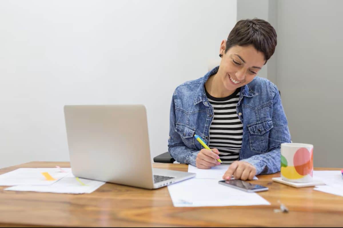 Pessoa estudando com laptop, anotando em papel, simbolizando preparação para concurso Banco do Brasil.