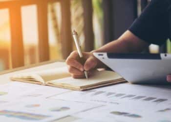 Estudante fazendo anotações em um caderno, priorizando tarefas e organizando estudos para manter o equilíbrio entre trabalho e vida pessoal.