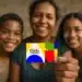 Mulher com dois filhos sorrindo, segurando o cartão do programa Bolsa Família