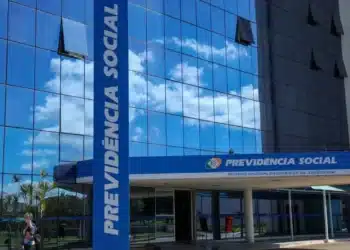 Imagem do prédio do INSS com fachada em vidro refletindo o céu, associado à revisão de benefícios.