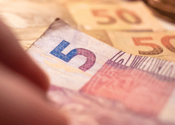 Notas de real brasileiro, com destaque para a nota de 5 reais e notas de 50 reais ao fundo.