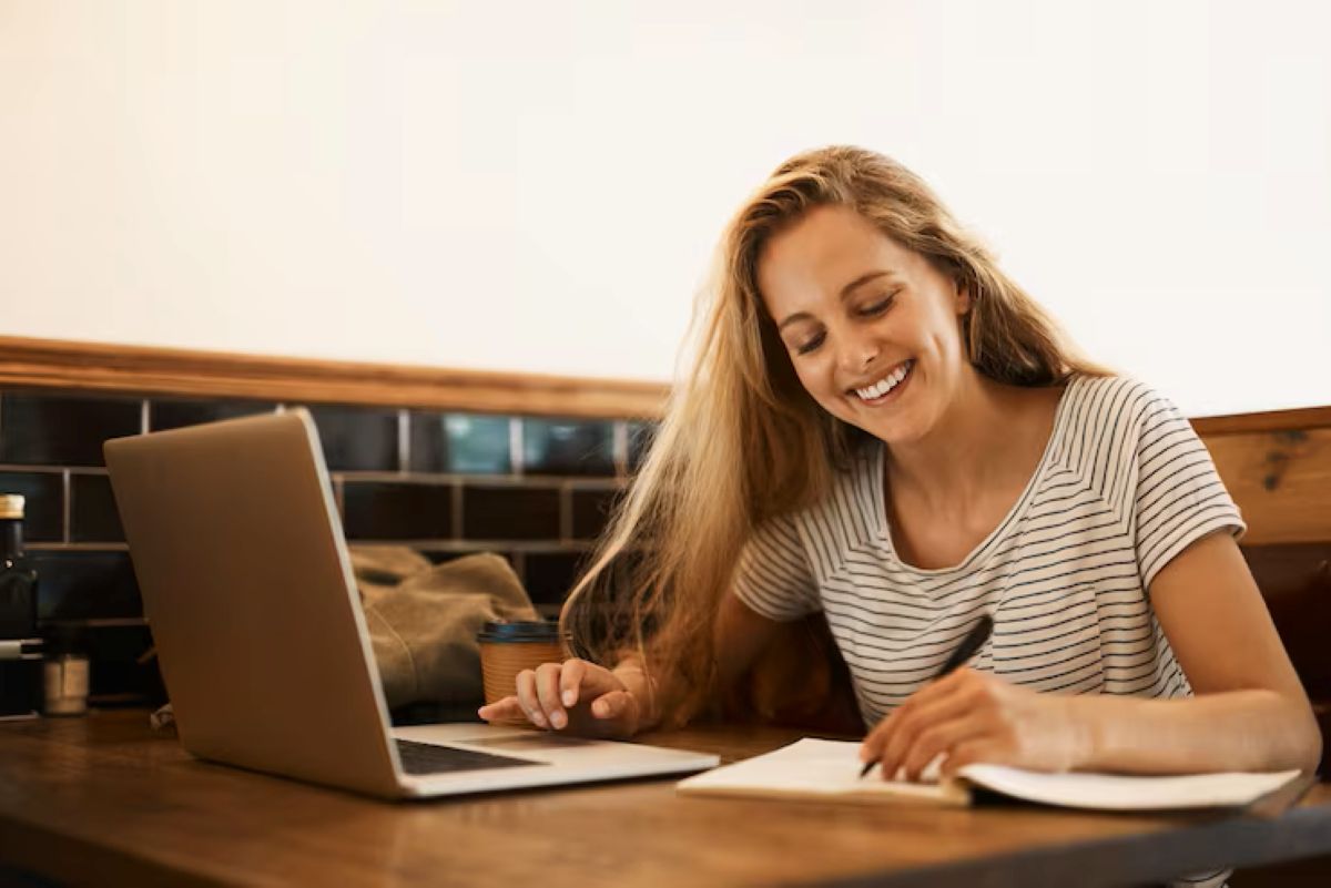 Mulher estudando com laptop e cadernos, se preparando para concurso público.