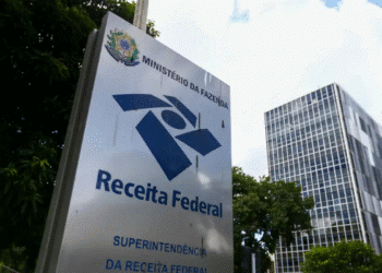 Placa da Receita Federal com edifício moderno ao fundo, Ministério da Fazenda Brasil