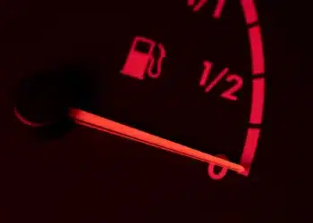 Imagem de um carro com o indicador de combustível na reserva, representando os riscos de dirigir com o tanque quase vazio.