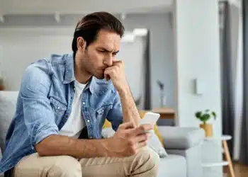 Homem concentrado olhando para o celular, refletindo sobre como reduzir o uso excessivo do aparelho.