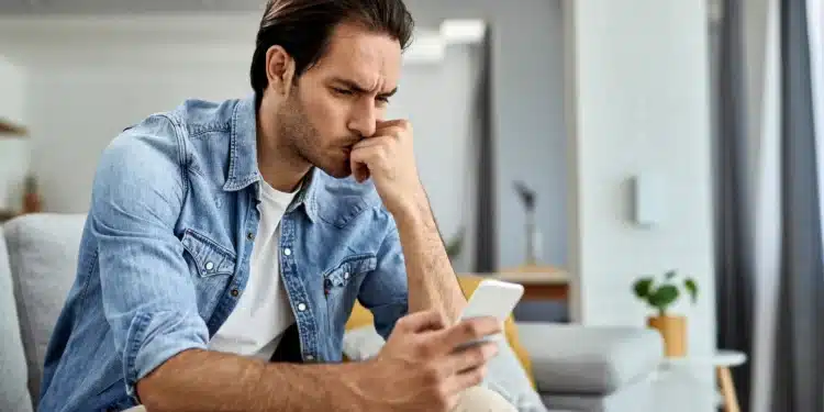 Homem concentrado olhando para o celular, refletindo sobre como reduzir o uso excessivo do aparelho.