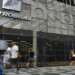 Fachada da sede da Petrobras com letreiro, grades e pessoas andando em frente em rua calçada